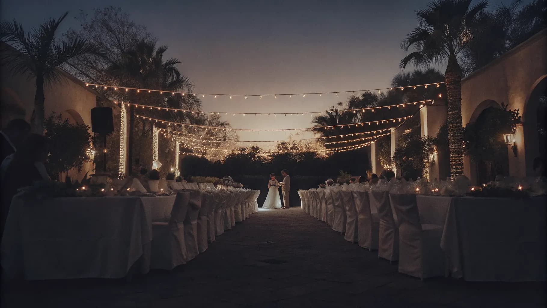 A garden wedding reception lit by warm string lights at dusk